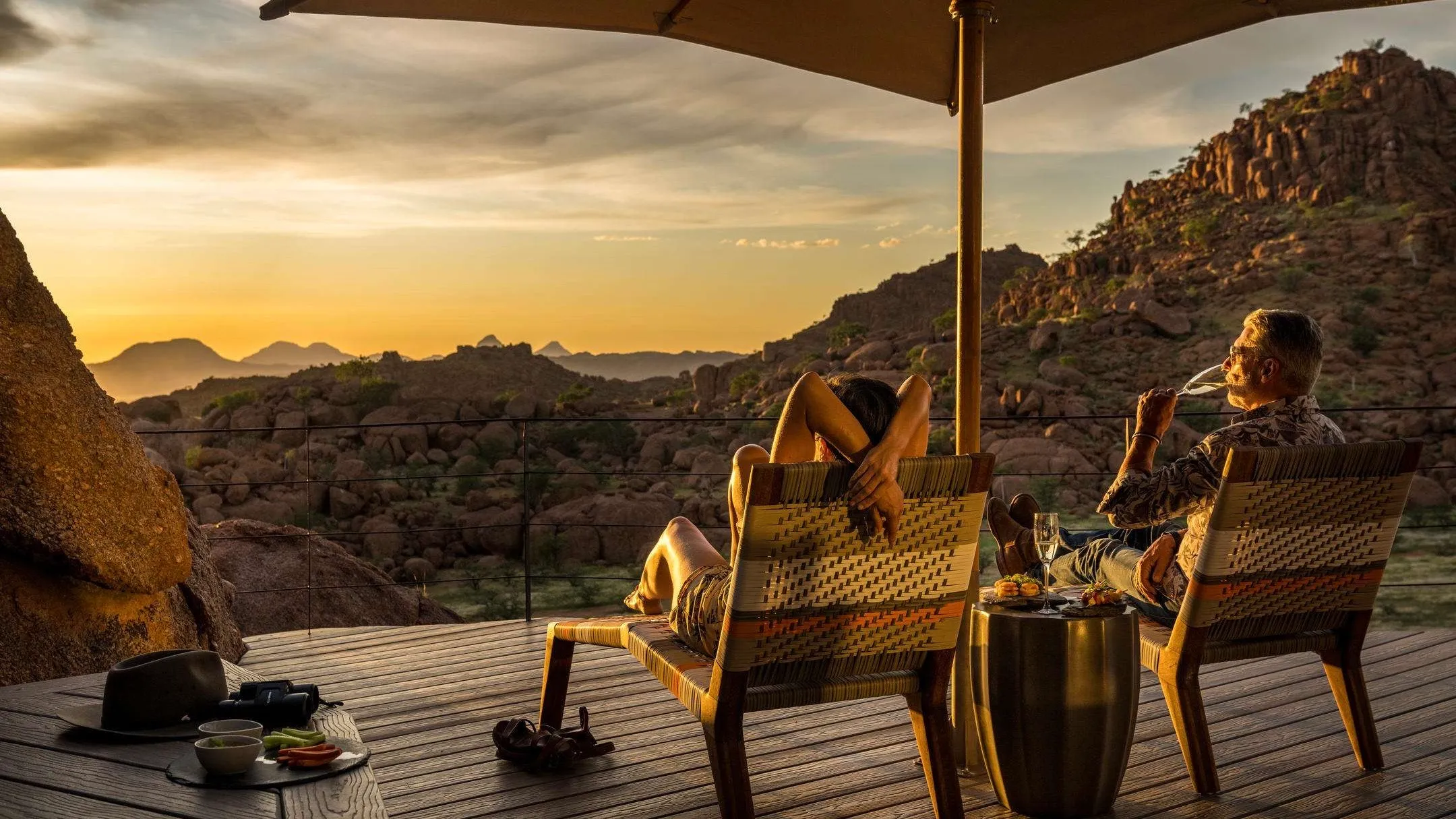 Couple enjoying sunset view with wine during safari